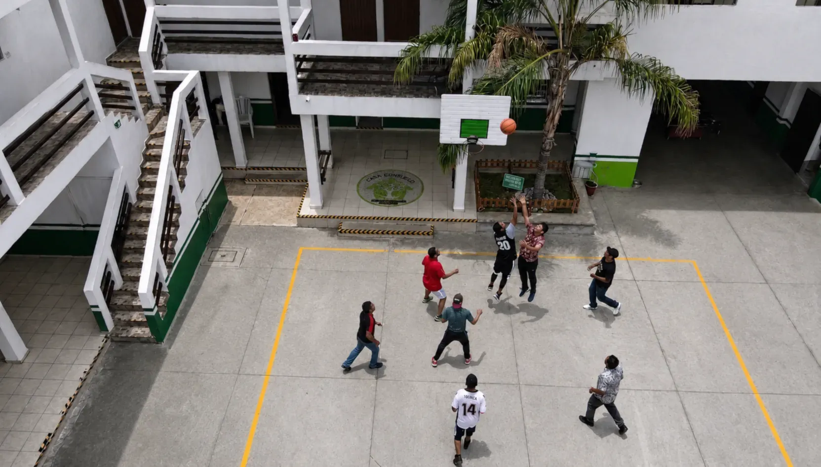 Residentes jugando baloncesto en el patio central durante actividad deportiva supervisada.