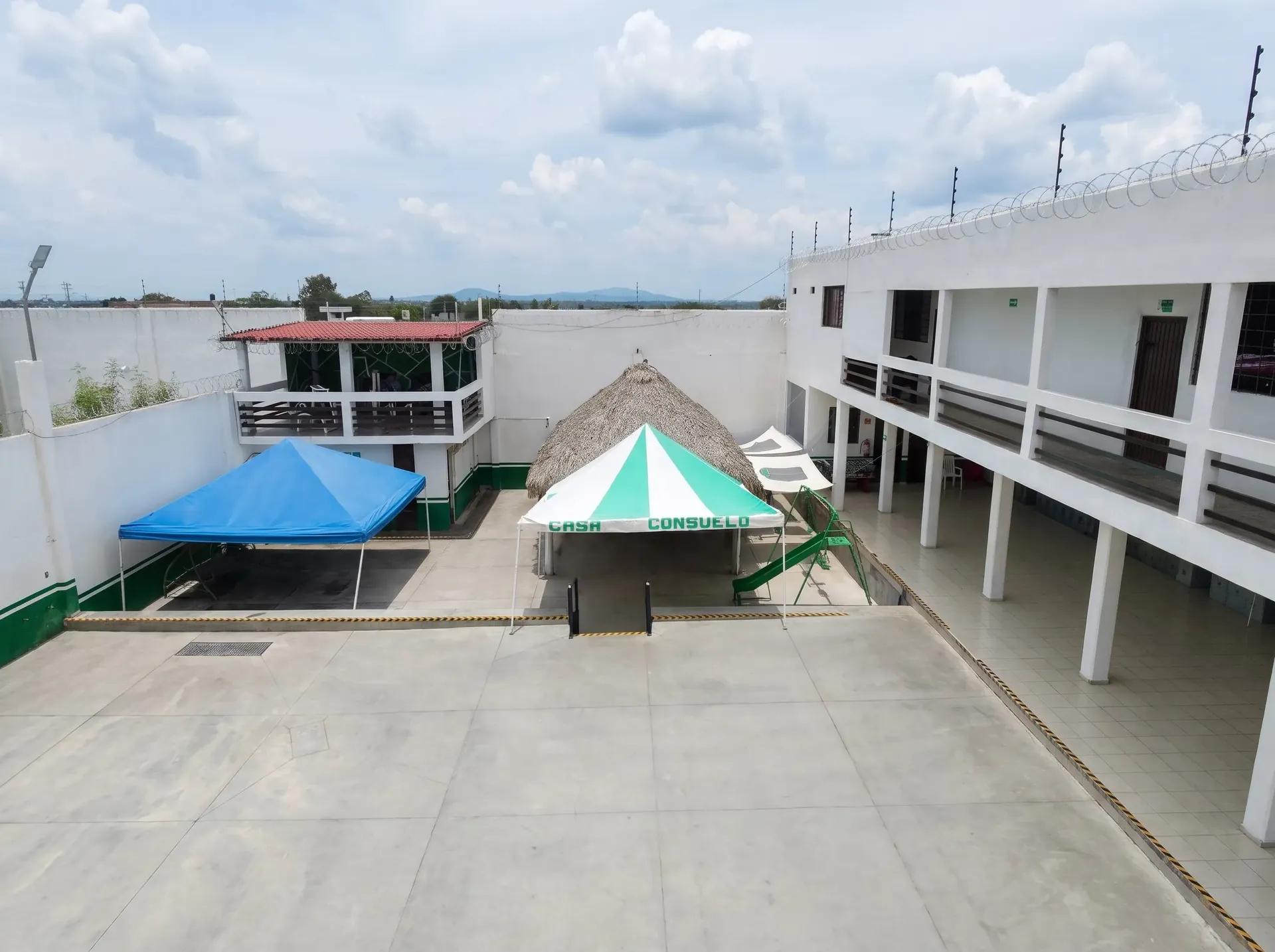 Área exterior techada con palapa tradicional y toldos en centro de rehabilitación.